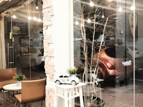A cozy indoor cafe scene with a small table, chairs, and a decorative car model near a window showing a parked car.