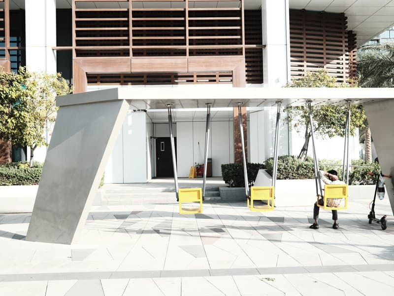 Modern outdoor seating area with yellow chairs under a sleek canopy in an urban setting.