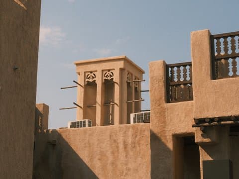 A traditional architectural structure with a wind tower against a clear blue sky.