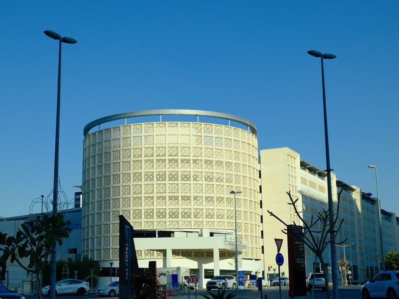 Modern circular building with a patterned facade under a clear blue sky.