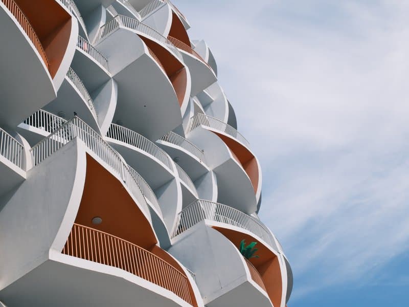 Close-up of a modern building facade with curved balconies against a blue sky.