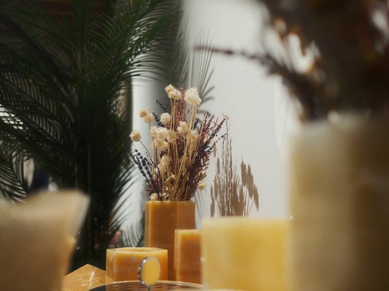 A soft-focus arrangement of candles and dried flowers in vases, creating a warm and inviting atmosphere.