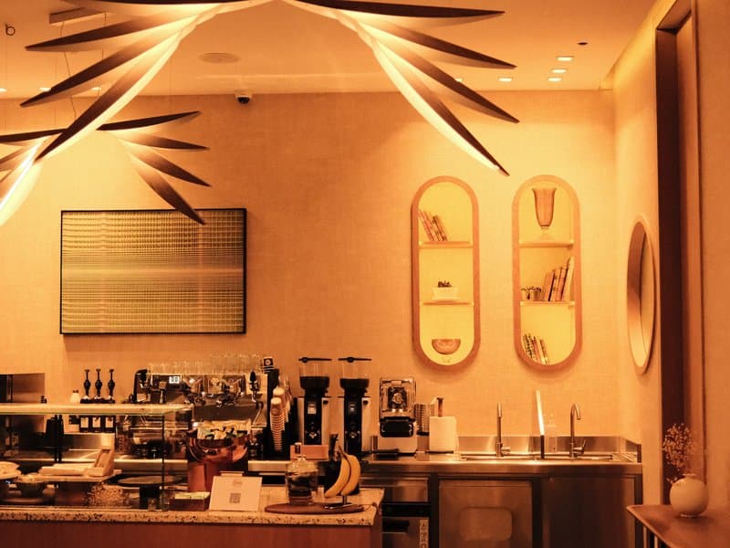 Interior of a stylish café with warm lighting, modern decor, and a coffee bar.
