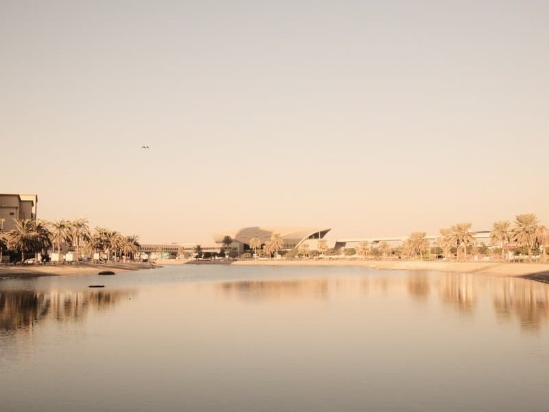 A serene river scene with soft pastel colors reflecting the landscape and buildings along the shore.