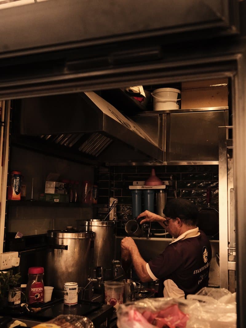 A chef working in a dimly lit kitchen, surrounded by cooking equipment and ingredients.
