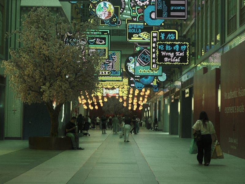 A vibrant indoor walkway adorned with colorful neon signs and a decorative tree.
