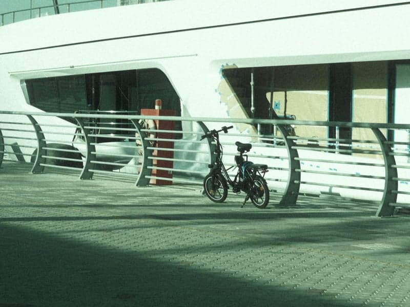 A parked bicycle next to a modern building with a sleek design and a railing in the foreground.