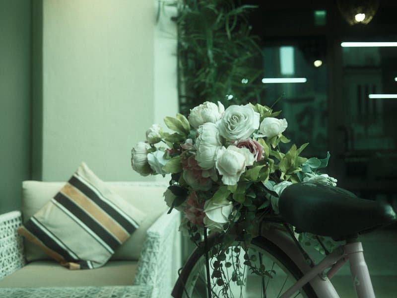 A vintage bicycle adorned with flowers, positioned next to a cozy seating area indoors.
