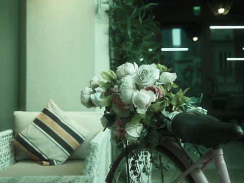A vintage bicycle adorned with flowers, positioned next to a cozy seating area indoors.