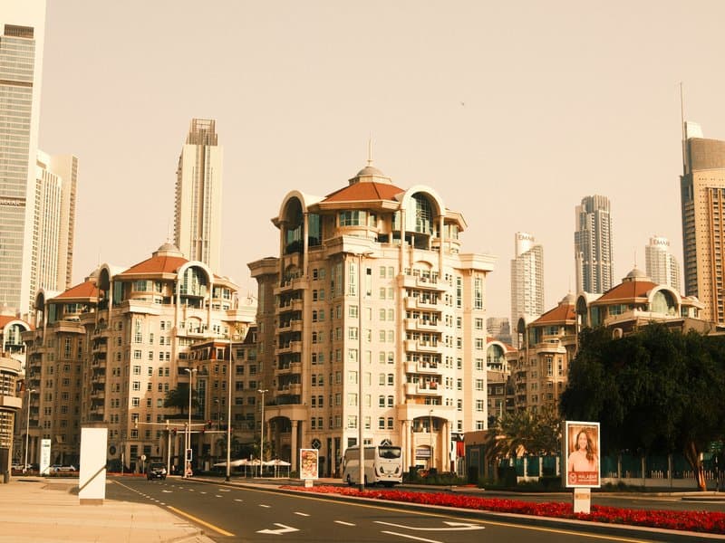 A modern urban scene featuring tall buildings and a distinct architectural structure with a warm color tone.