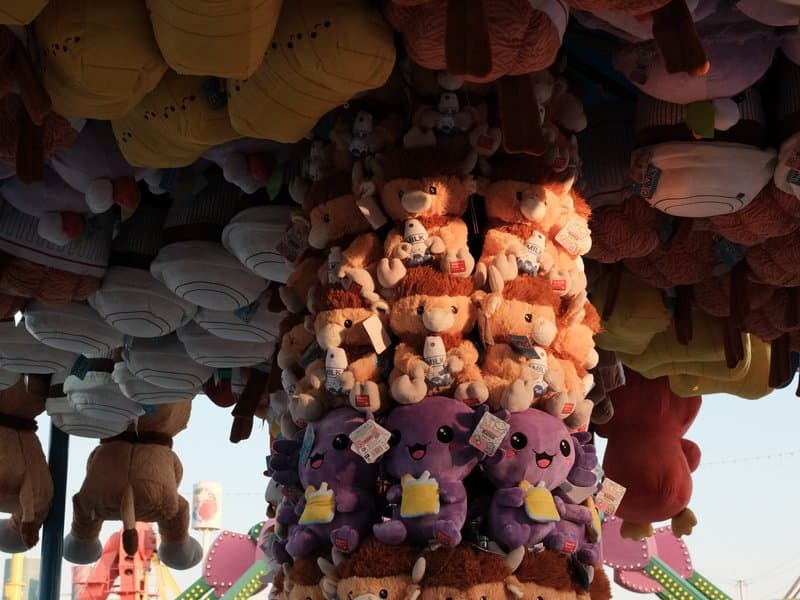 A colorful display of plush toys hanging from a carnival ride, showcasing various characters and colors.