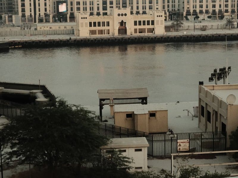 A view of a calm water body with buildings in the background and structures along the shore.
