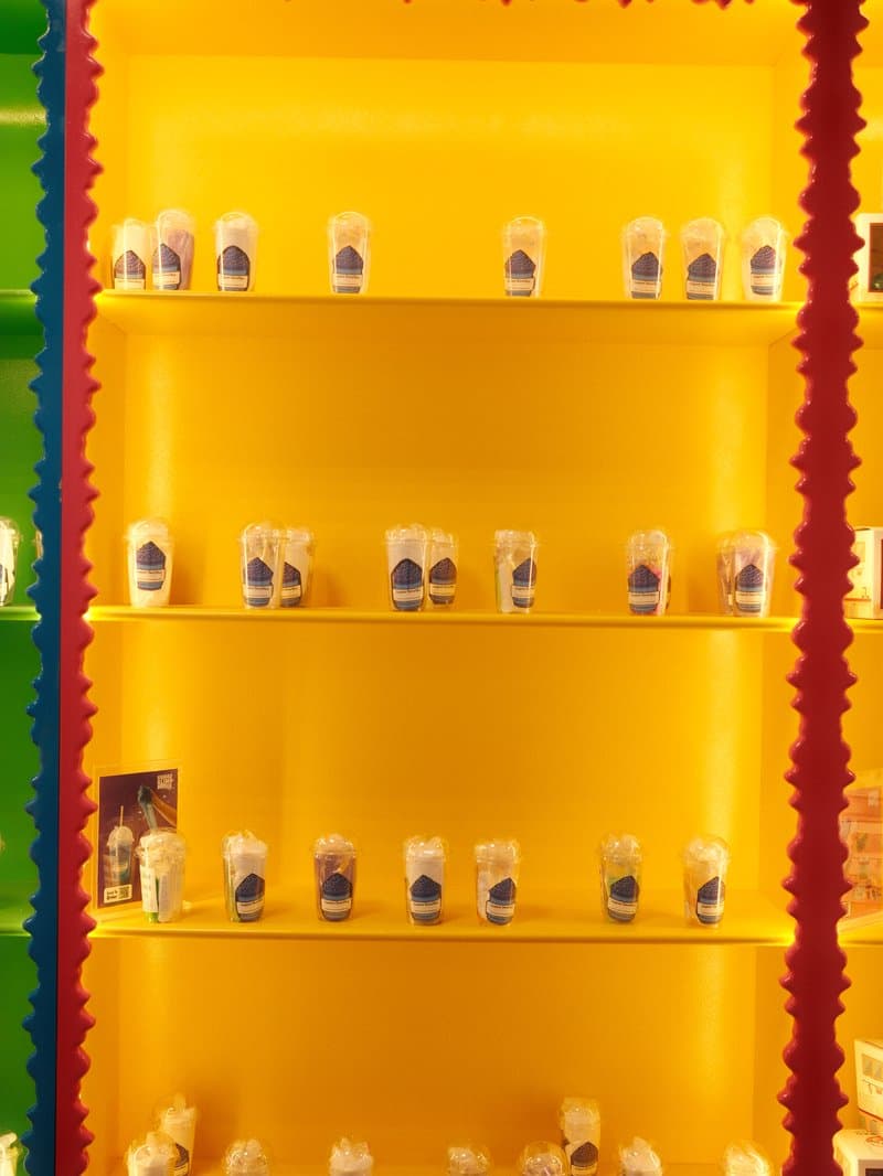 Colorful display of jars on shelves against a bright yellow background.
