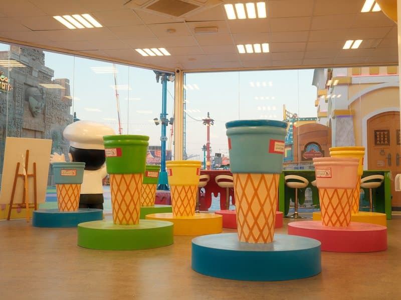 Colorful oversized ice cream cones in a bright indoor space with large windows.