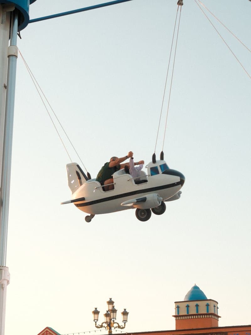 A child enjoying a ride in a small airplane suspended in the air against a clear sky.