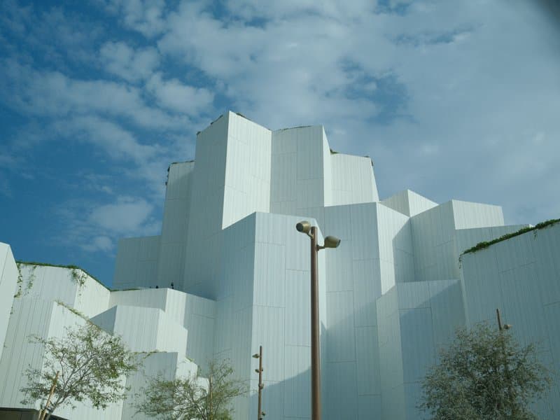 Abstract white architectural structure against a blue sky with scattered clouds.