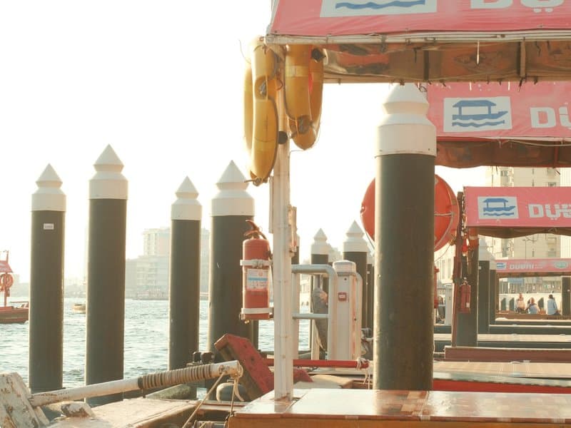 View of wooden docks with black and white poles, pink signage, and a hazy waterfront in the background.
