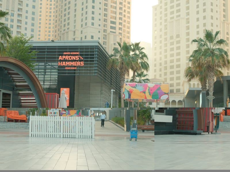 Urban scene featuring modern architecture with palm trees and colorful murals in a city setting.