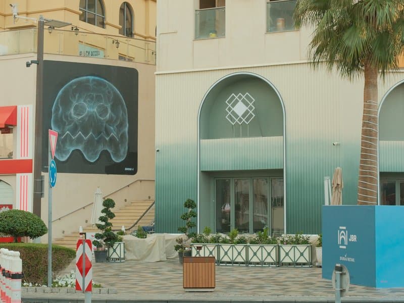 A modern urban scene featuring a large jellyfish mural on a building and a stylish storefront.