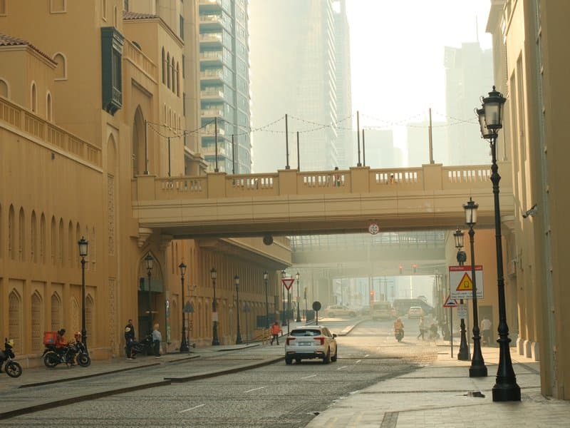 A quiet urban street with a bridge overhead, soft light filtering through a hazy atmosphere.