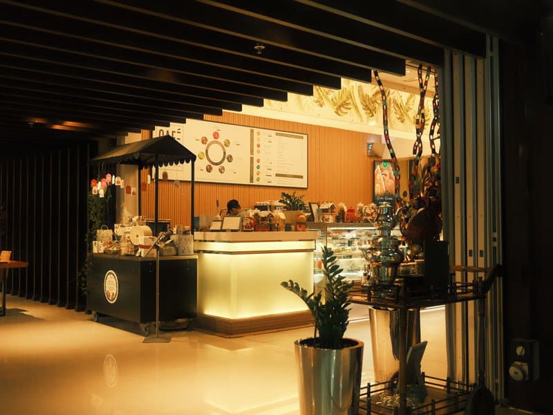 A cozy indoor café with warm lighting and a display of pastries and drinks.