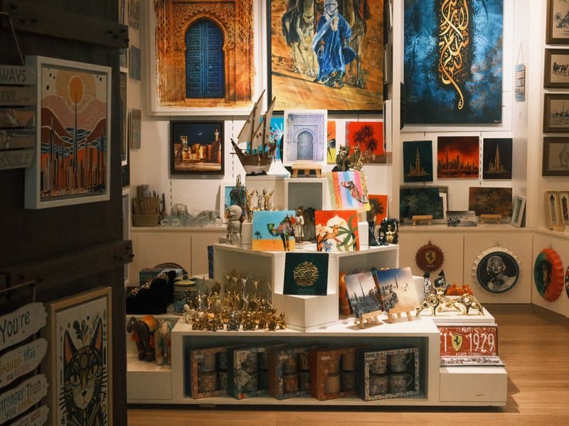 Art gallery display featuring various paintings and sculptures in a well-lit indoor setting.