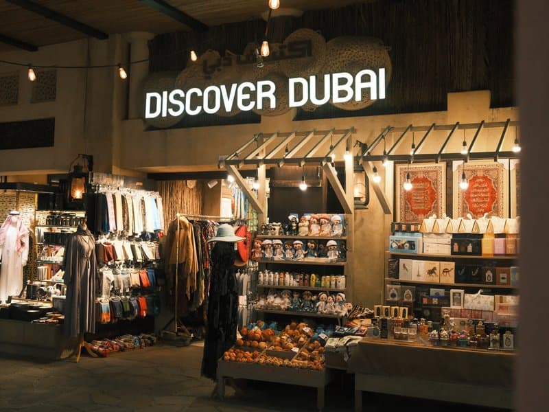 A shopfront displaying souvenirs and local products with a sign that reads 'Discover Dubai'.