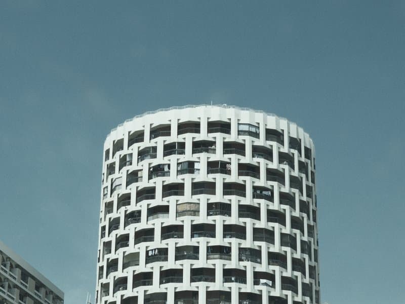 A modern circular building with a patterned facade against a clear blue sky.