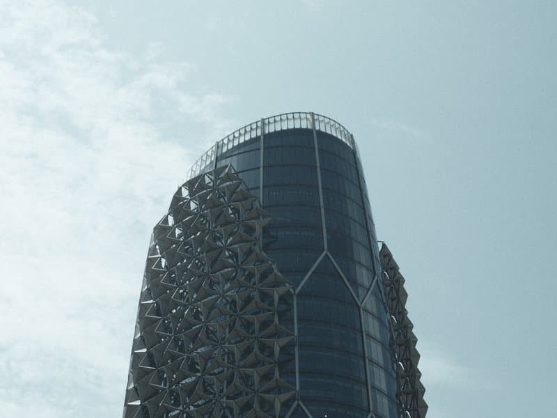 A modern skyscraper with intricate patterns on its facade against a pale blue sky.