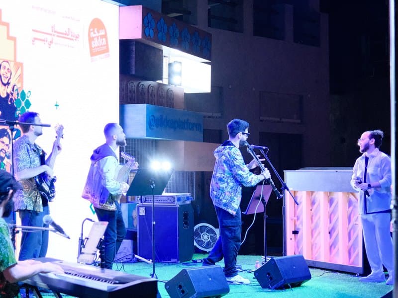 A live music performance featuring a band with instruments and a singer on stage at night.