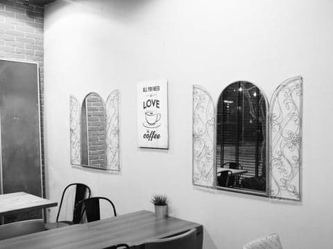 A cozy indoor cafe scene featuring decorative windows and a motivational poster on the wall.