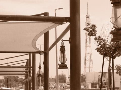 A vintage lantern hanging under a canopy with a tower in the background, creating a nostalgic atmosphere.