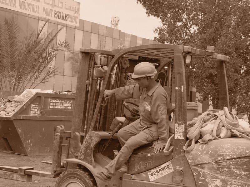 A worker operating a forklift loaded with materials in a construction area.
