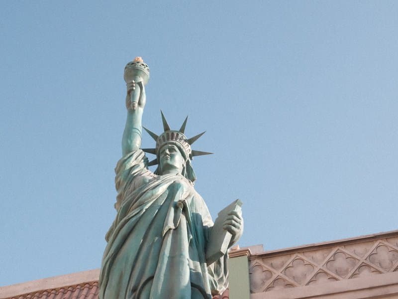 Close-up of the Statue of Liberty against a clear blue sky, holding a torch and a tablet.