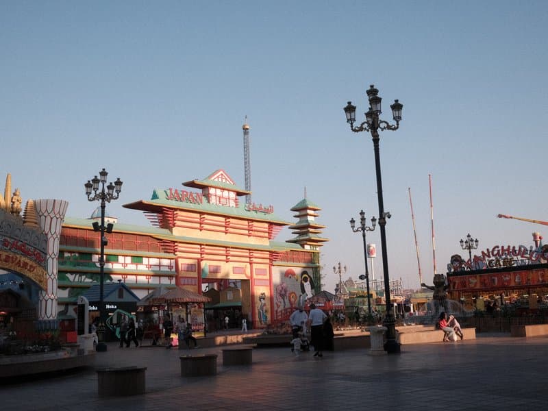 Colorful amusement park entrance with decorative architecture and street lamps under a clear sky.