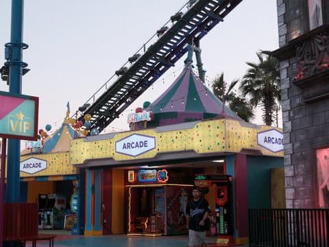 Colorful arcade entrance with a carnival theme, featuring bright lights and a roller coaster above.