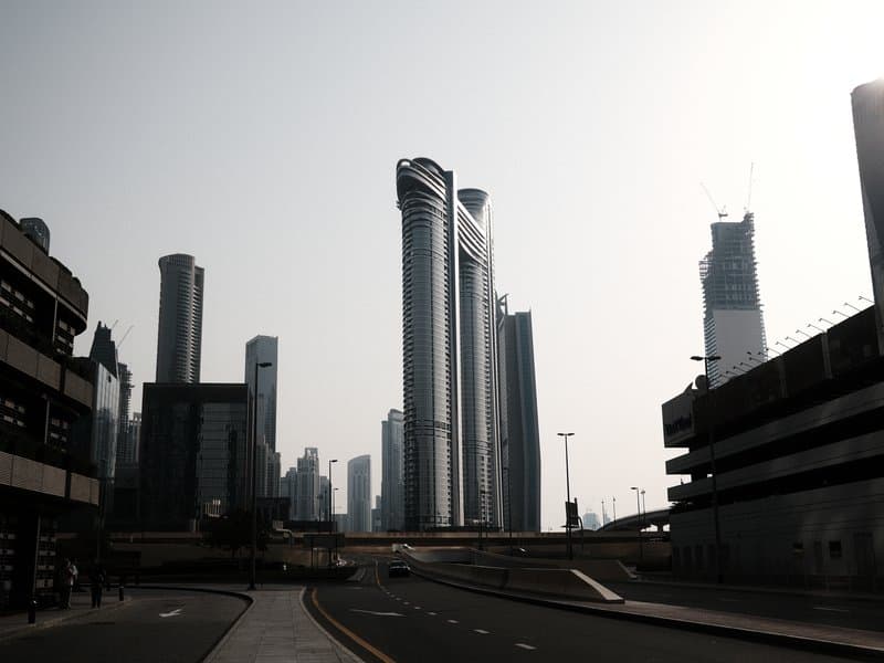 Silhouetted skyscrapers against a bright sky in an urban setting.