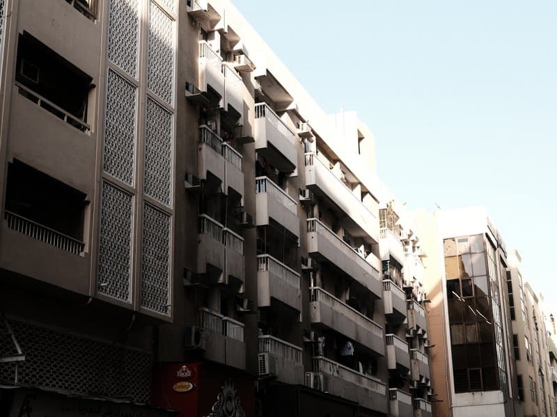 A street view of urban buildings with air conditioning units and a clear blue sky.