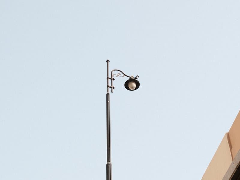A streetlight mounted on a tall pole against a clear blue sky.