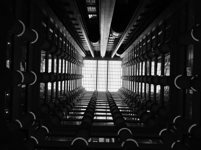 Looking up at a modern building's interior with beams and lights creating a geometric pattern.