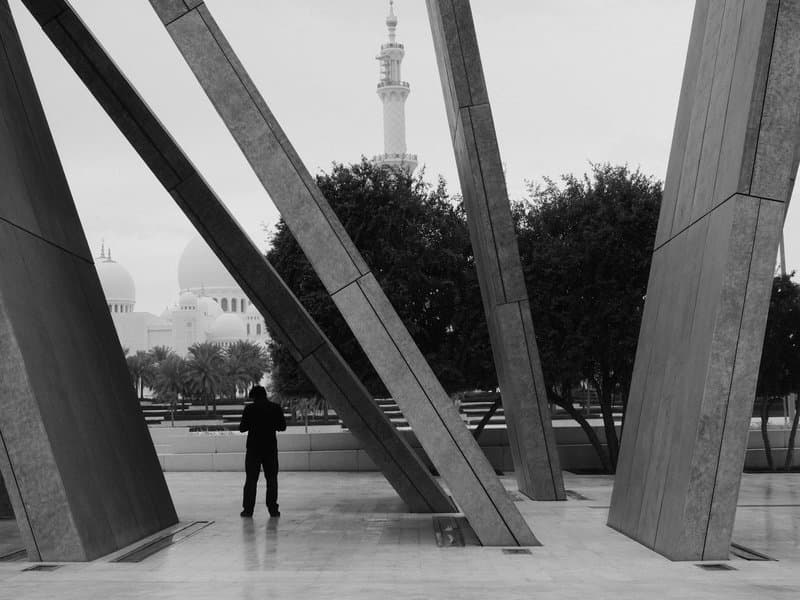 A person standing among large metal structures with a city skyline in the background.
