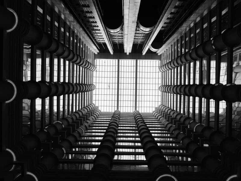 View looking up through a modern architectural structure with beams and circular elements.