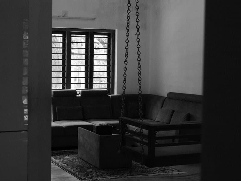 A monochrome interior scene featuring a cozy living room with a swing chair and large windows.