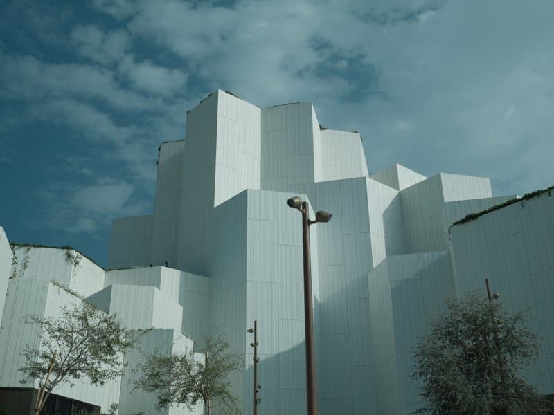 Abstract white architectural structures against a cloudy sky.