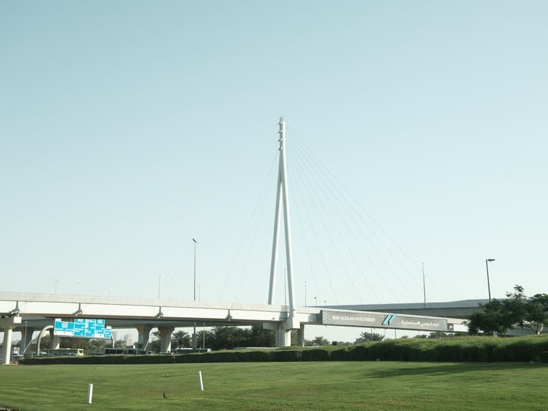 A modern cable-stayed bridge against a clear sky, with green grass in the foreground.