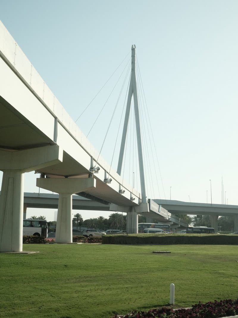 A modern cable-stayed bridge with a clear blue sky in the background, surrounded by green grass.