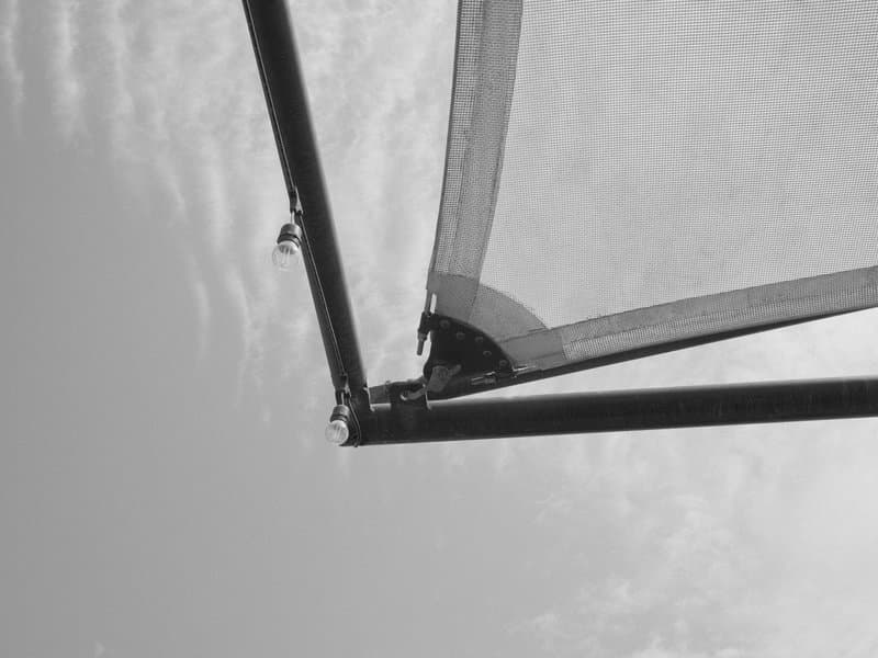 Close-up view of a tent frame against a cloudy sky, highlighting the structure and fabric.