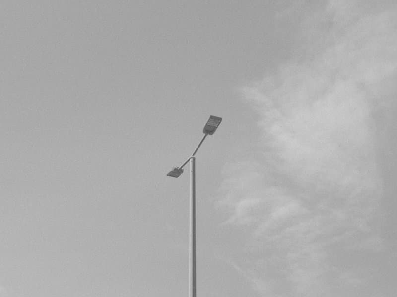 A solitary street lamp against a cloudy sky in black and white.