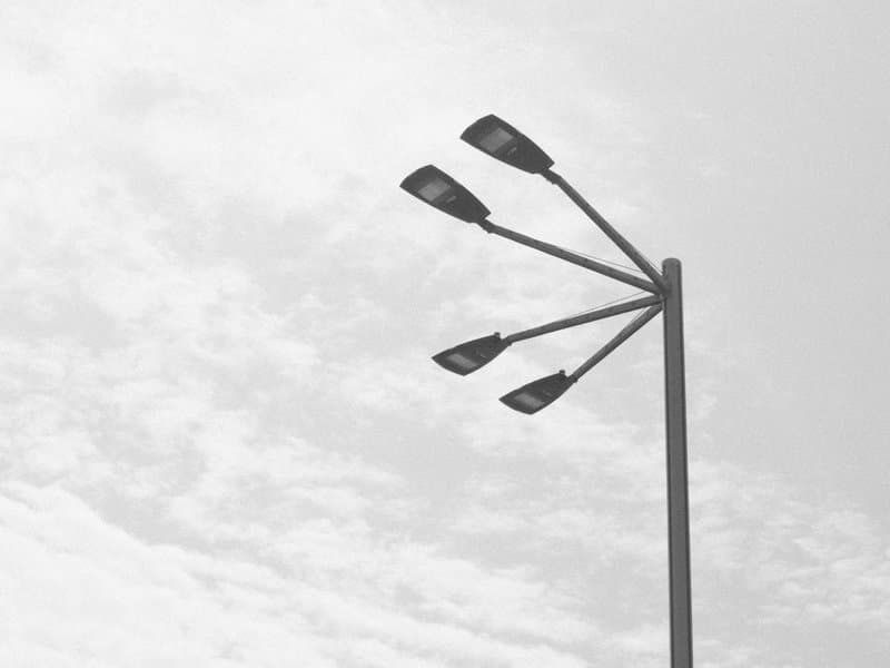 A tall street lamp with multiple light fixtures against a cloudy sky.