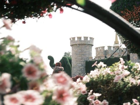 A castle partially obscured by blooming flowers in a garden setting.